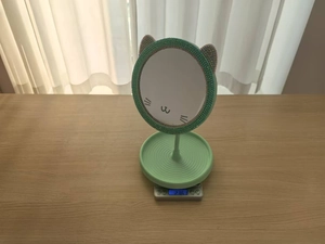 Creative green cat-eared makeup mirror with storage base weighing 236g on a digital scale