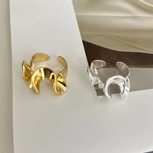 Dettaglio di anelli aperti ritorti in oro e argento con trama in ottone lucido