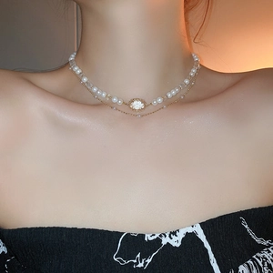 Close-up of double-layer necklace with gold-plated diamond pendant and pearl strand
