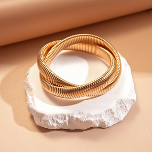 Macro view of two twisted gold snake bone bracelets with textured spring coil design