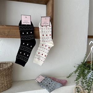 Détails de chaussettes en tricot avec motifs de cœurs rouges et formes géométriques