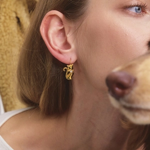 Close-up of a model wearing a gold cat-shaped earring with a small crystal stone