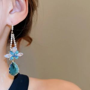 Close-up of gold drop earrings with blue gradient flower and crystal waterdrop
