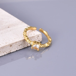 Gold plated titanium steel open ring with zircon stone on textured stone surface