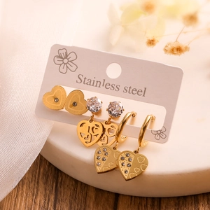 Close-up of three pairs of gold stainless steel heart earrings with zircon details on card