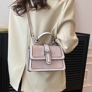 Detail shot of a vintage pink floral embossed crossbody bag worn by a model in a beige blazer