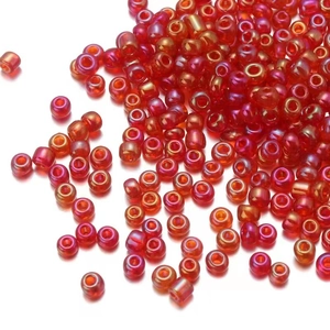 Close-up of small red glass seed beads with iridescent finish for jewelry making