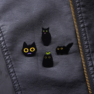 Set of four cute black cat enamel pins styled on a leather jacket for a minimalist look