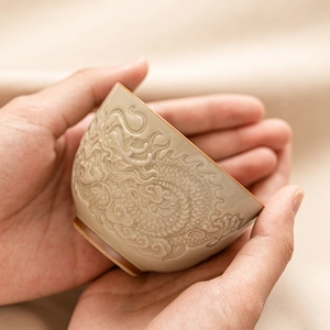 Ceramic teacup with relief dragon patterns held in hands, Chinese style tea art cup