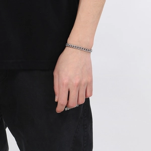 Gros plan d'un bracelet gourmette en acier inoxydable argenté sur un poignet masculin