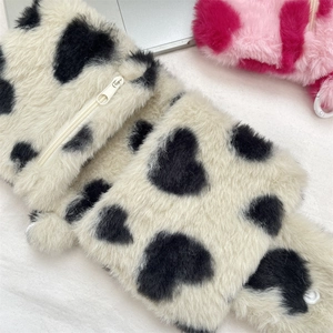 Close-up of plush faux fur pouch with black heart pattern and white zipper detail