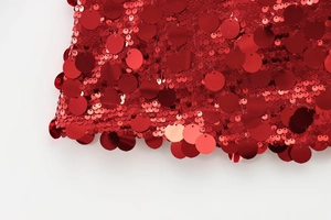 Detailed close-up of vibrant red round sequins stitched on A-line skirt fabric