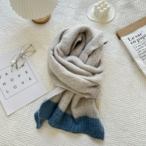 Detail view of a soft knit scarf in beige and blue with cozy lifestyle accessories