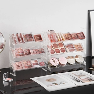 Clear acrylic tiered makeup organizer for lipstick and eyeshadow on a sleek black base