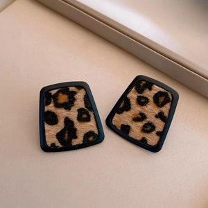 Detail of round leopard print earrings with black matte borders and plush texture finish