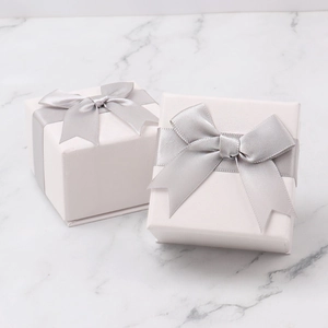 Elegant square jewelry gift boxes with silver bow ties on premium marble surface