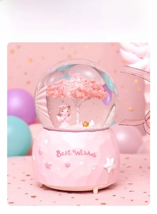 Detailed view of pink cherry blossom crystal ball music box with angel and gold star