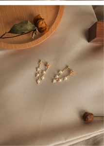 Close-up of elegant freshwater pearl tassel earrings on champagne silk background