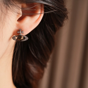 Détail de la boucle d'oreille Saturne avec pierre œil de tigre et zircons sur l'oreille
