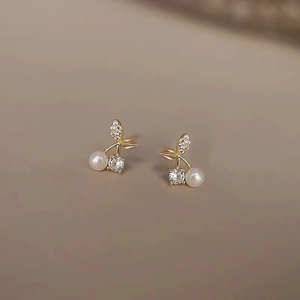 Detail of cherry pearl stud earrings in gold finish with sparkling cubic zirconia leaves