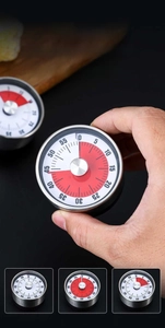 Mechanical kitchen timer with a red visual countdown dial held in hand for easy operation