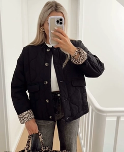 Detail einer schwarzen Steppjacke mit Leopardenmuster-Manschetten und Pattentaschen