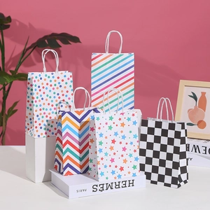 Five assorted pattern paper gift bags with twisted rope handles on a pink background