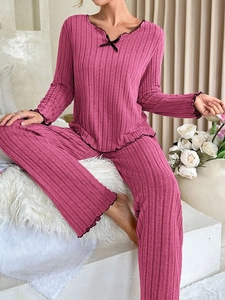 Detail of ribbed knit loungewear set with ruffled edges and black bow accent in magenta