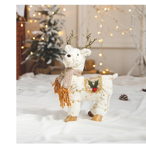 Detail of a white plush reindeer figurine with golden antlers and a festive brown scarf