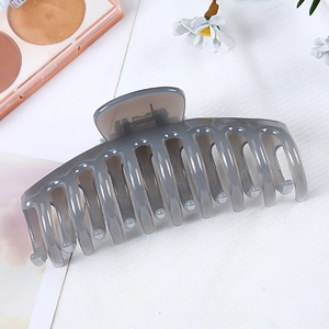 Top view of large translucent grey hair claw clip with interlocking teeth on white fabric