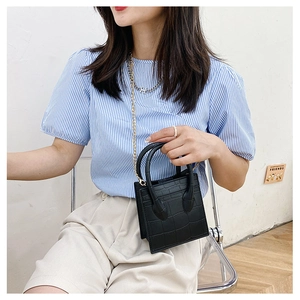 Mini black crocodile pattern square bag with gold chain strap shown on model lifestyle