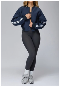 Dettaglio della giacca blu scuro con strisce sulle maniche e pantaloni yoga grigi
