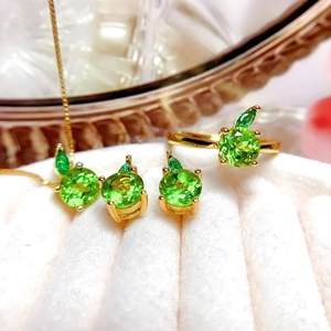 Elegant gold apple jewelry set with green gemstones in a white velvet box
