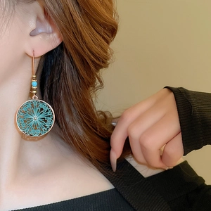 Detail of bohemian hollow bronze earrings with turquoise beads on model
