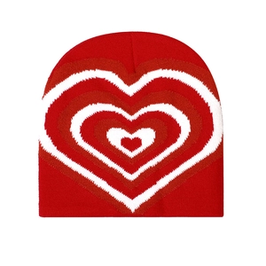 Macro detail of the red knitted beanie showing the soft texture and jacquard heart pattern