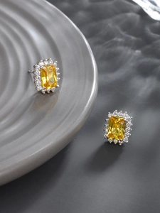 Macro shot of rectangular emerald-cut yellow gemstone earrings with halo diamonds