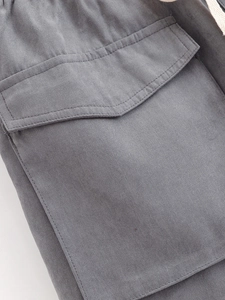 Detail of dark grey cargo shorts featuring utility flap pocket and drawstring waist