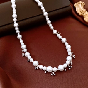 Detail view of pearl necklace with snowflake zircon pendants on dark silk background