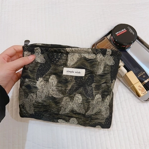 Nahaufnahme der Schmetterlingsstickerei und Textur der goldenen Jacquard-Kosmetiktasche