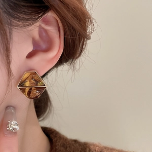 Close-up of amber resin hexagonal earrings with gold plating on a model's ear