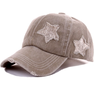 Detail of khaki distressed baseball cap with sequined star patches and frayed edge design