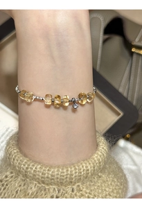 Detailed shot of beaded bracelet with citrine stones and zircon charm on wrist