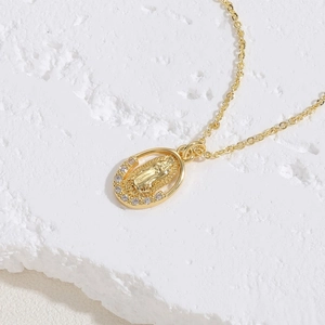 Detail of gold Virgin Mary pendant with sparkling zircon inlay on white rock background