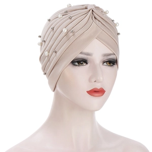 Detail of beige pleated turban with white pearls and silver beads on elastic fabric