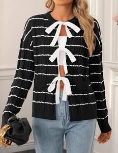 Detail of white ribbon bow ties on a black and white striped knit cardigan for women
