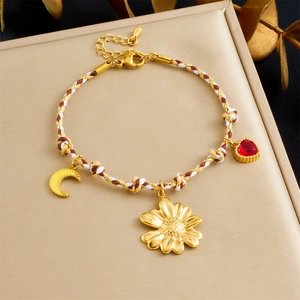 Bohemian braided cord bracelet with gold daisy, moon, and red heart pendant charms