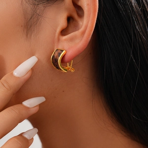 Close-up of golden C-shaped leopard print earrings worn by a model for a stylish look