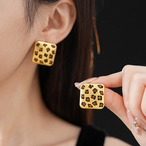 Detail of square gold leopard print earrings with amber crystals on model's ear