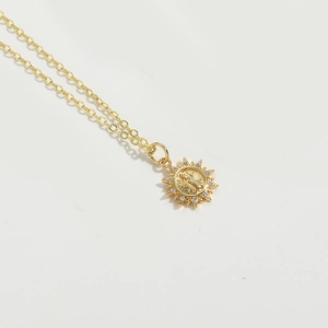 Close-up of gold starburst necklace with religious relief and white zircon inlay