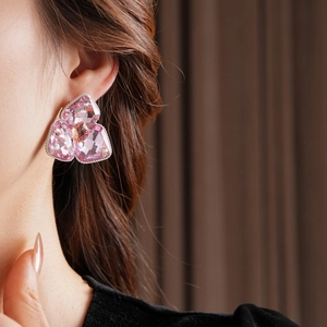 Detail showing high-end pink crystal flower earrings worn with shiny silver base and gems
